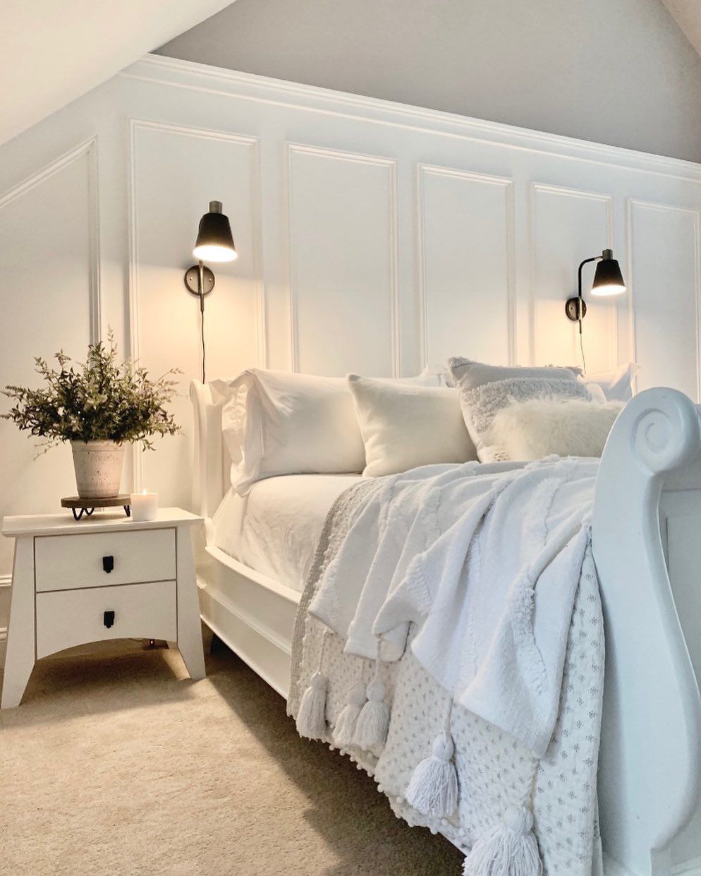 lit à baldaquin et table de nuit incurvée dans une chambre à coucher blanche