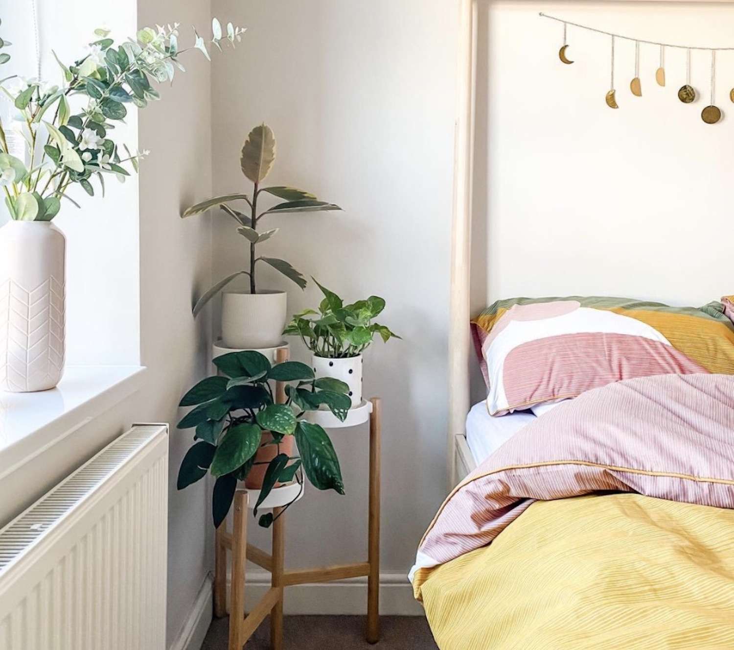 chambre à coucher moderne avec des plantes sur la table de chevet, couette jaune et rose