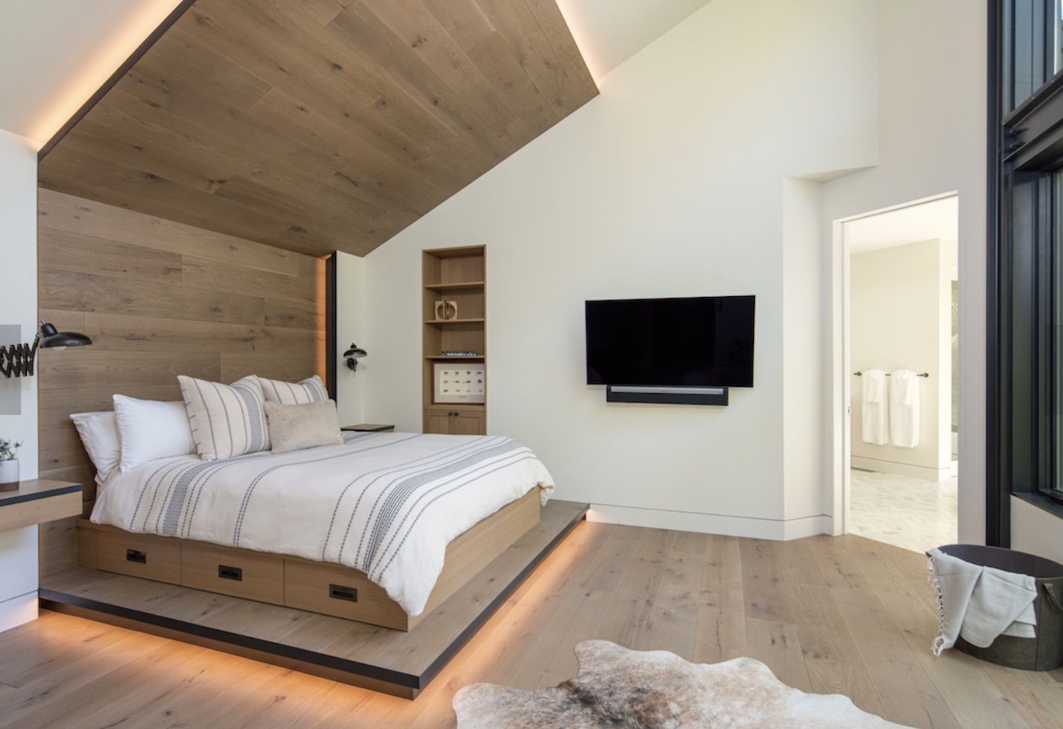 chambre à coucher moderne avec mur et cadre de lit en bois clair, plancher en bois, plan ouvert