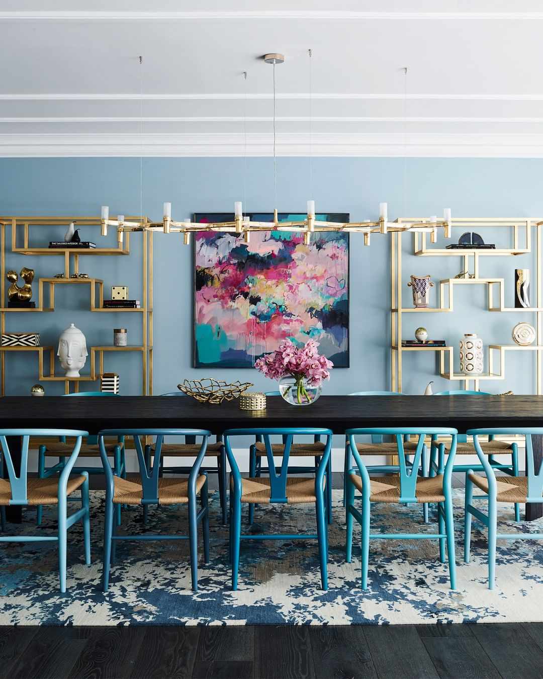Table de salle à manger avec des chaises bleues et une bibliothèque dorée
