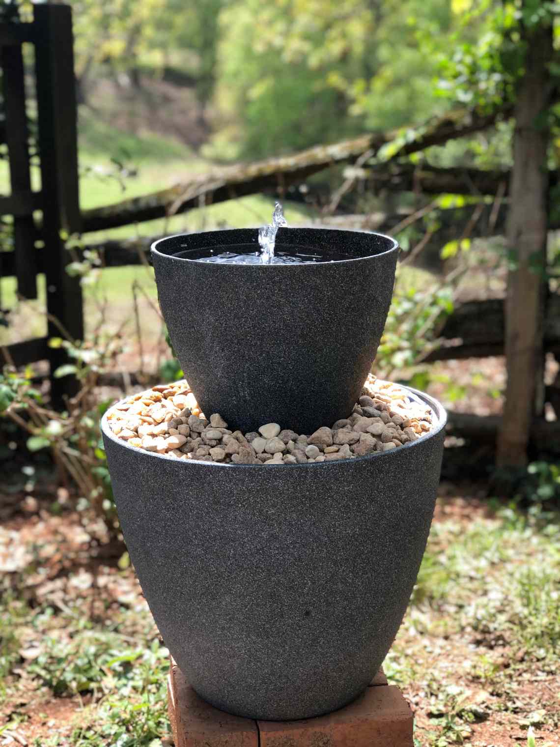 L'eau jaillit d'une fontaine d'extérieur noire à deux niveaux.