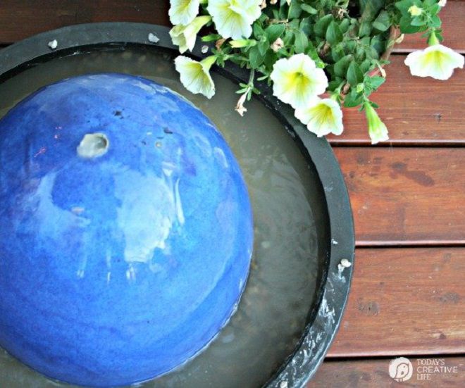 Une fontaine à bulles bleu vif sur une terrasse en bois.