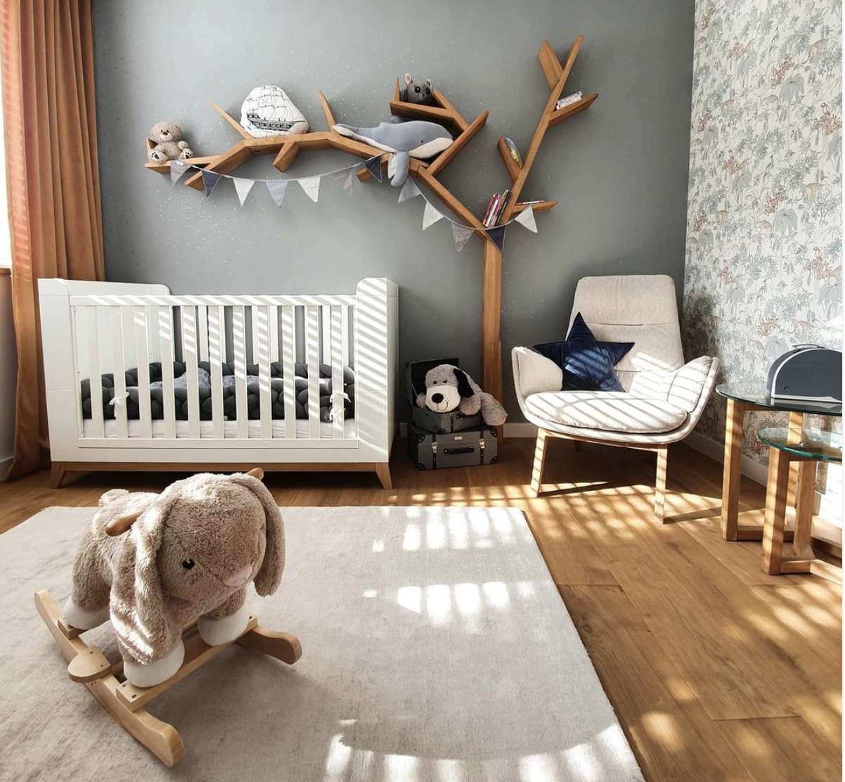 chambre d'enfant avec étagères en forme d'arbre, murs gris, chaise dans le coin, berceau blanc