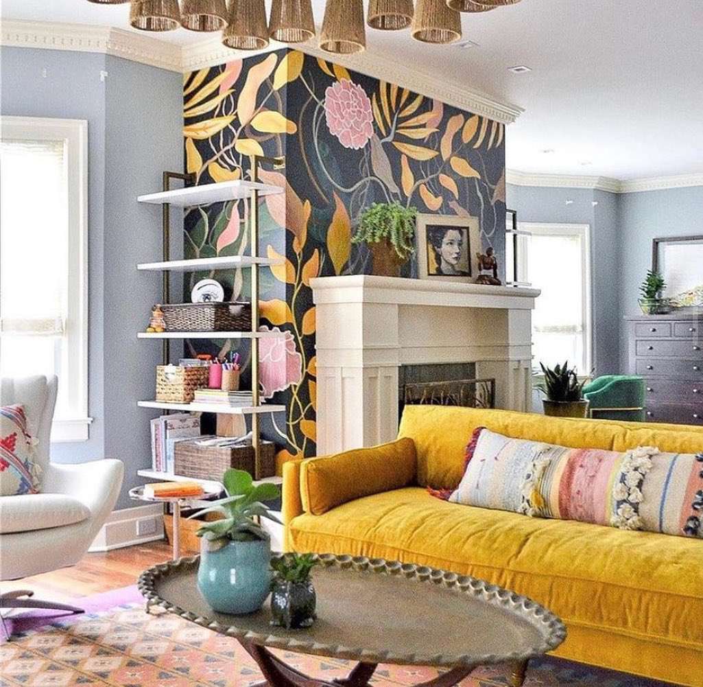 Un salon lumineux et audacieux avec un papier peint à fort contraste et un canapé en velours jaune.