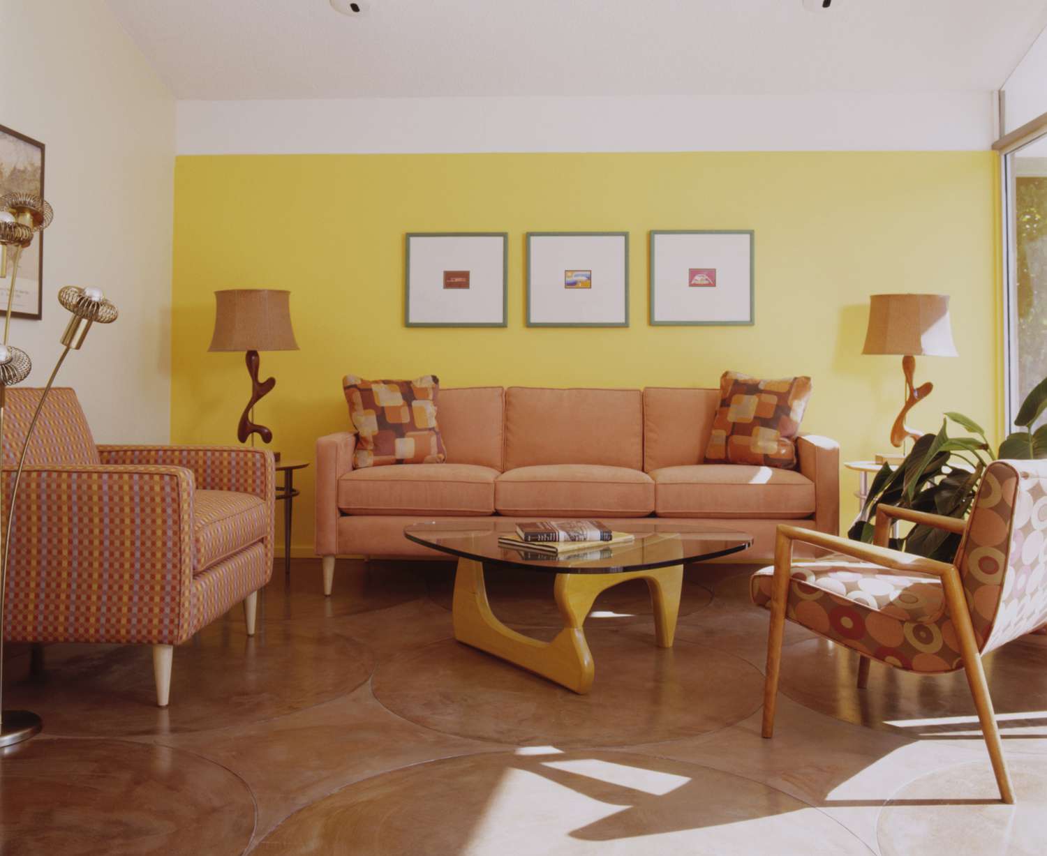 Un salon lumineux de style moderne du milieu du siècle avec des meubles pêche/orange et un mur d'accent jaune.