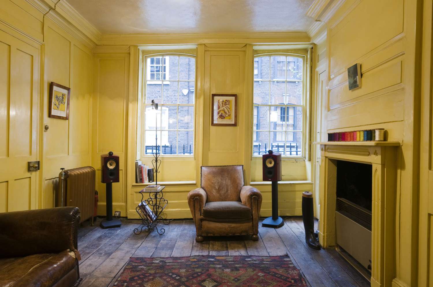 Un petit salon d'appartement avec de hauts plafonds et des moulures historiques entièrement peints en jaune.