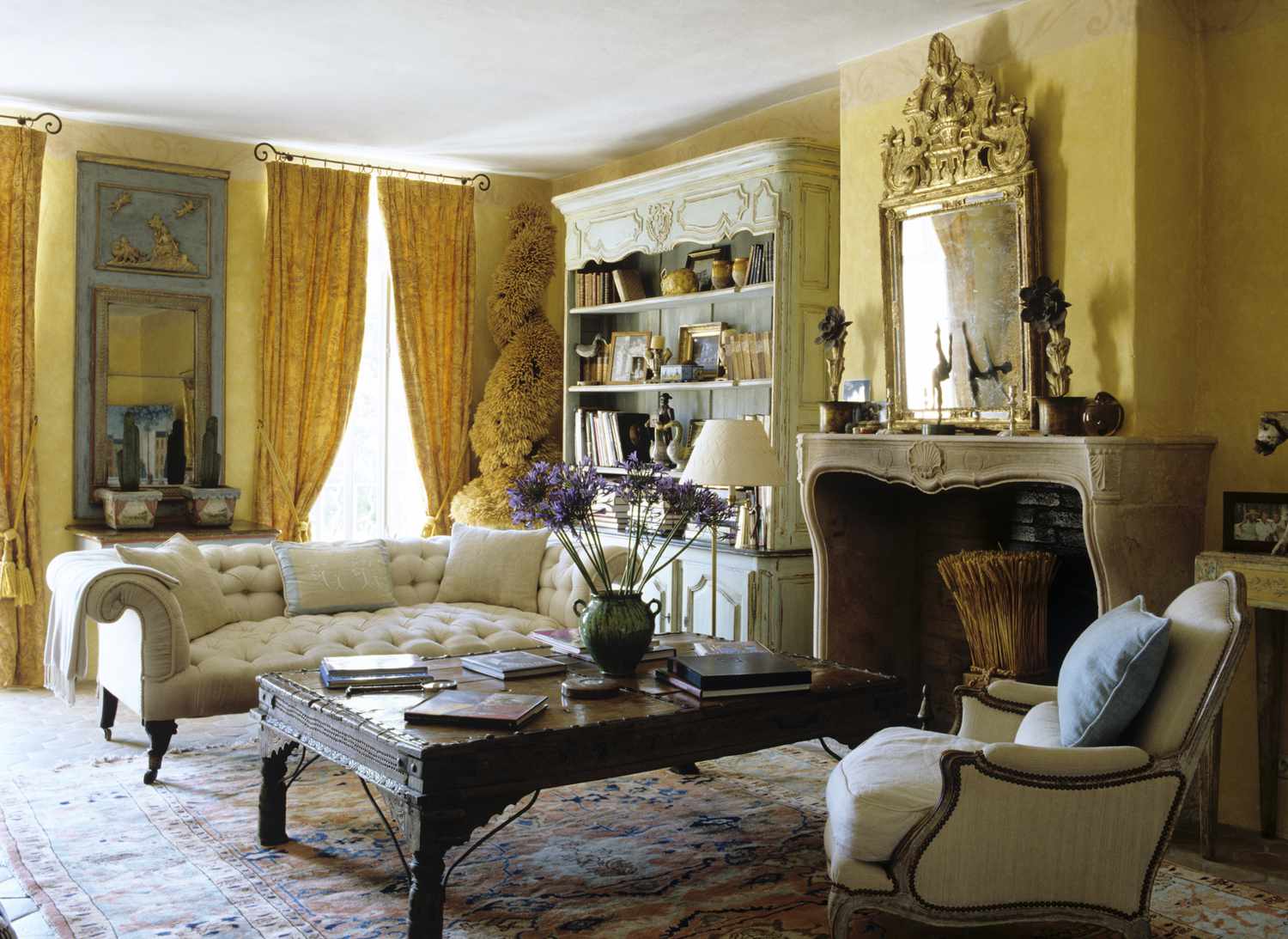 Un salon de style victorien avec des murs jaune tendre, des touches d'or et du bois foncé.