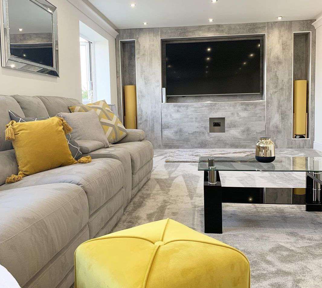 Un salon gris et jaune avec une grande télévision.