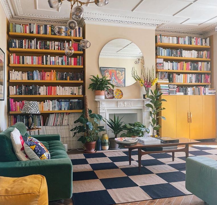 Des bibliothèques jaunes du sol au plafond dans un salon éclectique.