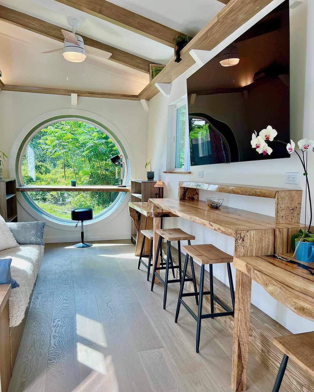 Idées de rangement dans une petite maison, sièges de bar, fenêtre circulaire, TV grand écran