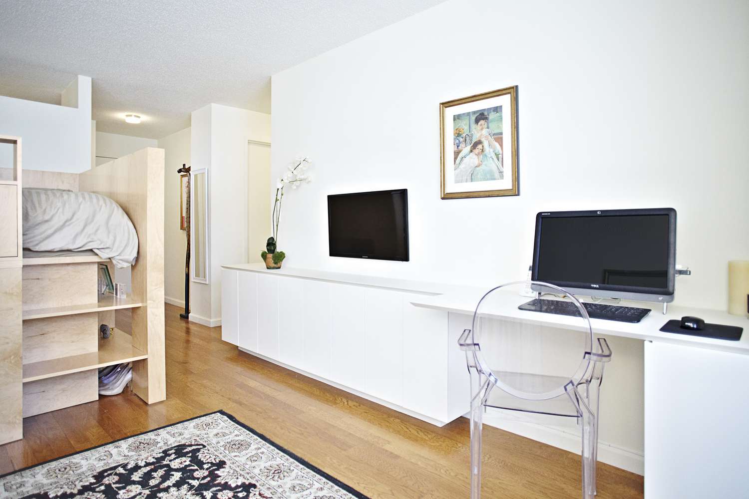 Un cagibi sur mesure pour le lit d'un studio avec une télévision et un ordinateur sur le bureau.