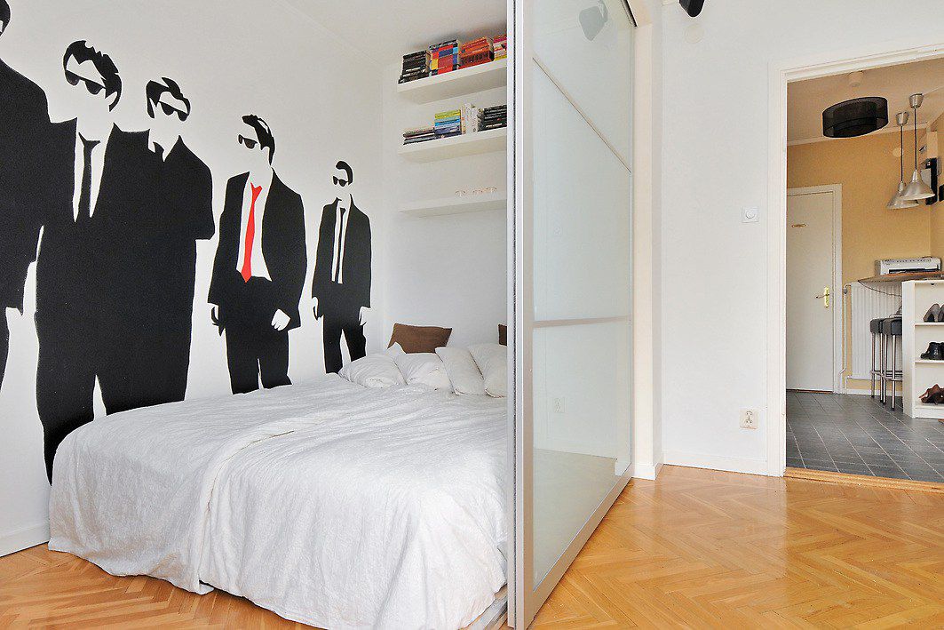 Studio avec une cloison pour séparer la chambre à coucher qui a des silhouettes d'hommes sur le mur.