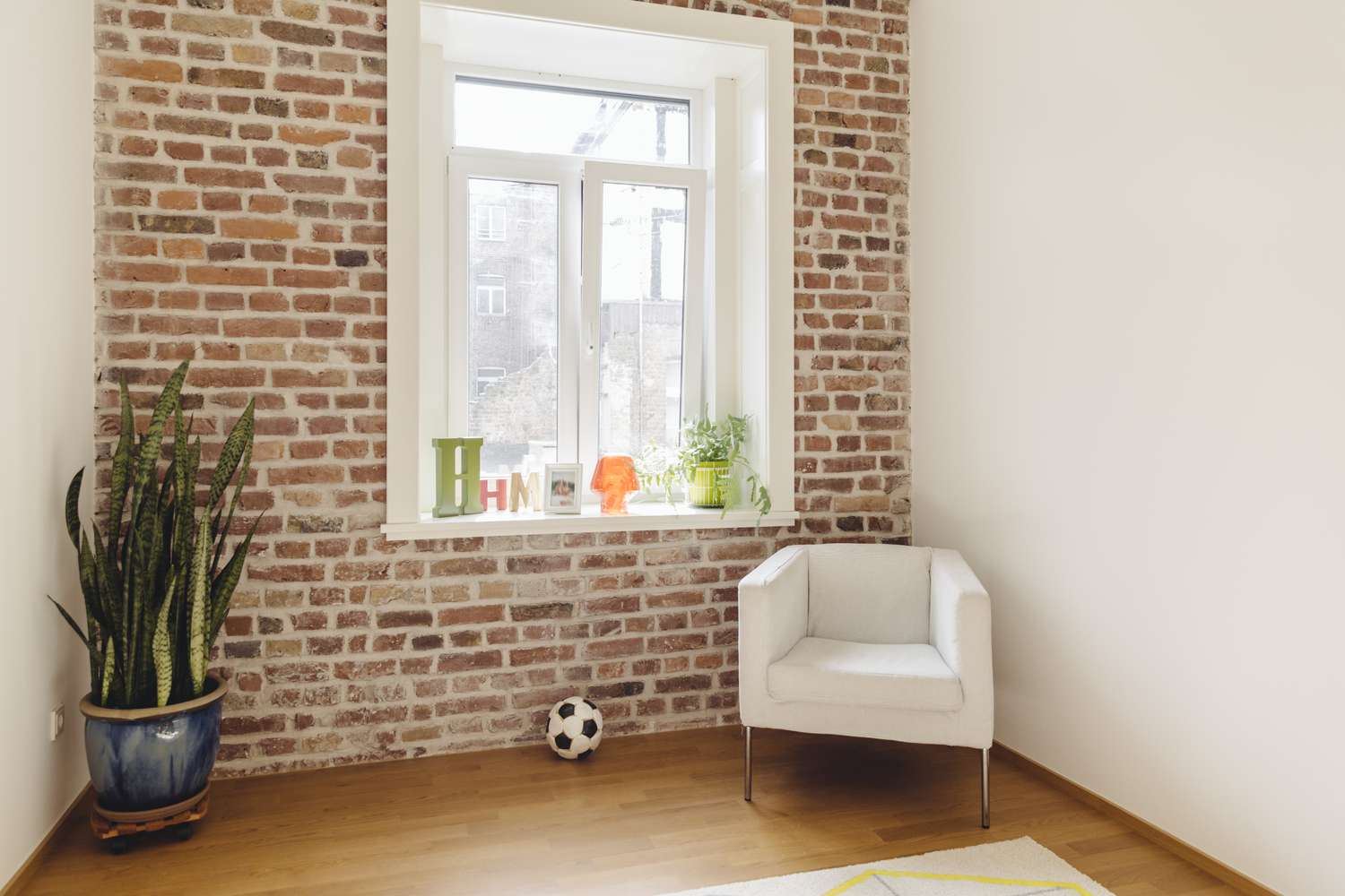 mur d'accent en briques avec plante en pot et chaise beige