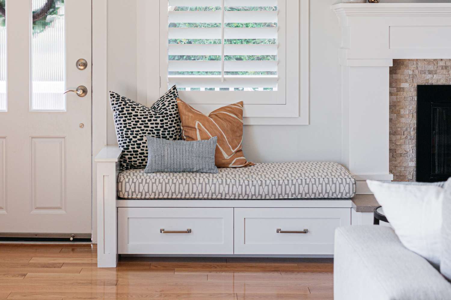 Siège de fenêtre avec tiroirs blancs, coussins et oreillers à motifs multiples