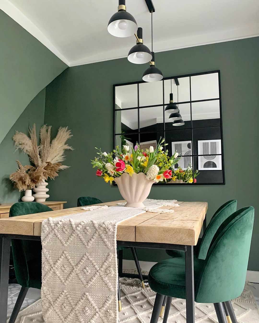 Salle à manger avec murs verts et chaises en velours vert.