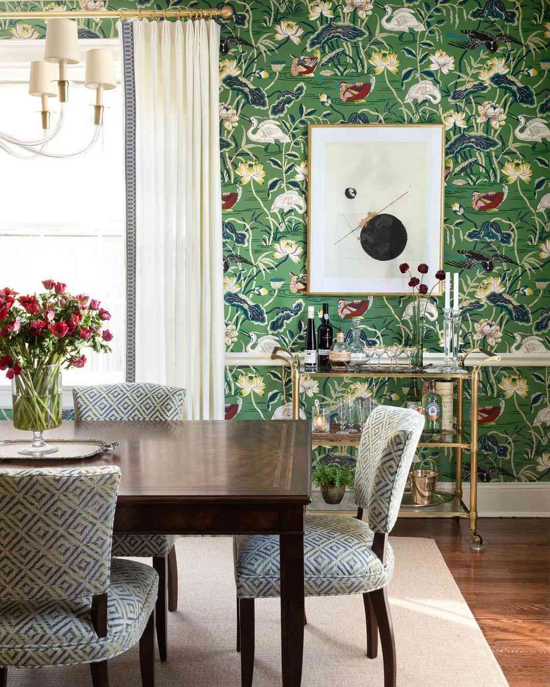 Salle à manger avec papier peint vert très contrasté.