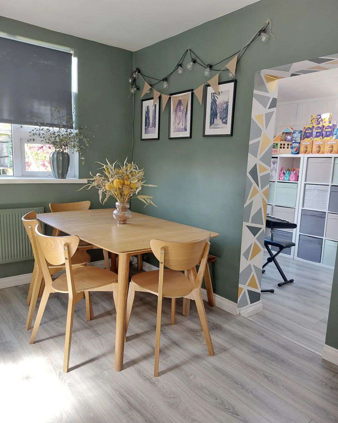 Salle à manger avec des murs verts et une amusante peinture murale.