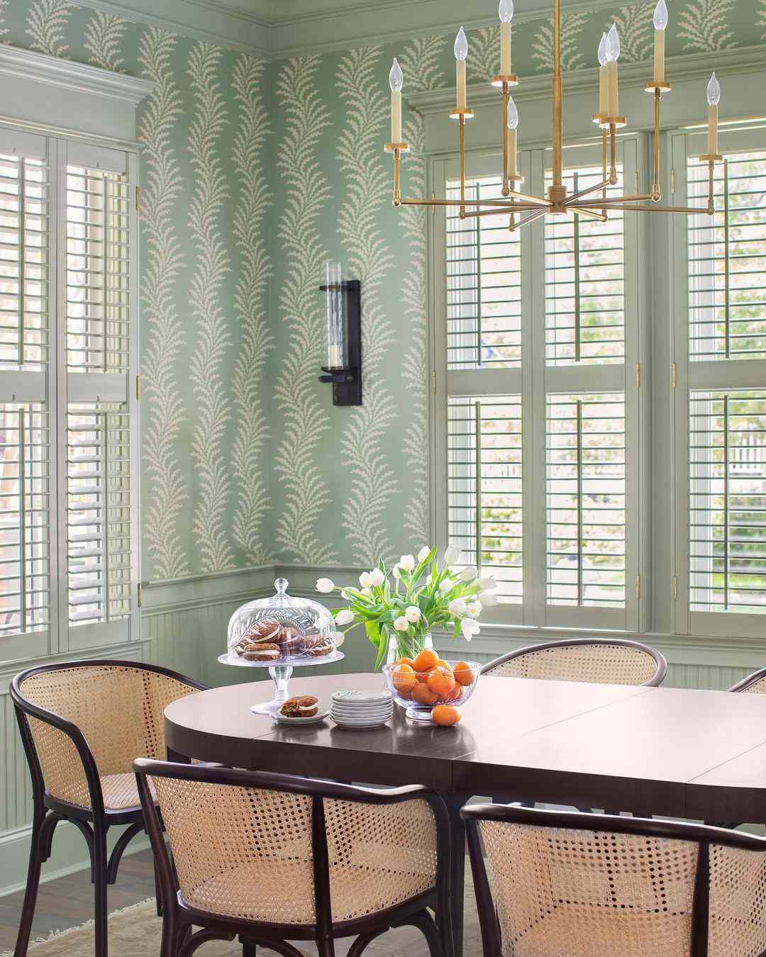 Salle à manger verte avec papier peint demi-mur.