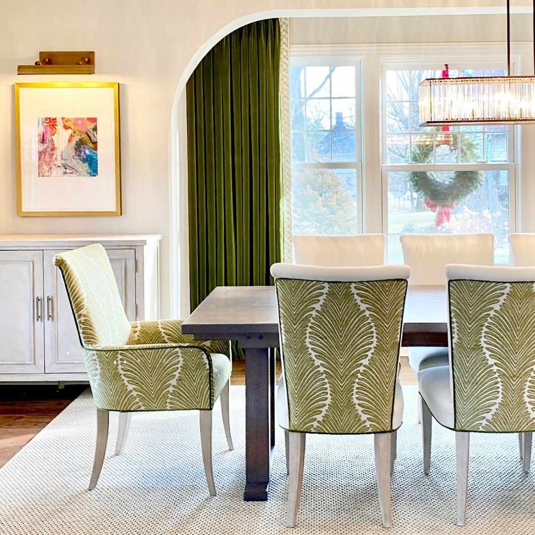 Salle à manger avec chaises et rideaux verts.