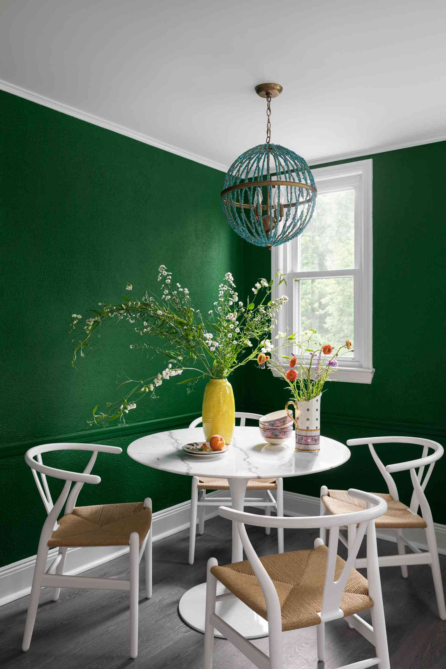 Salle à manger verte avec peinture murale audacieuse.