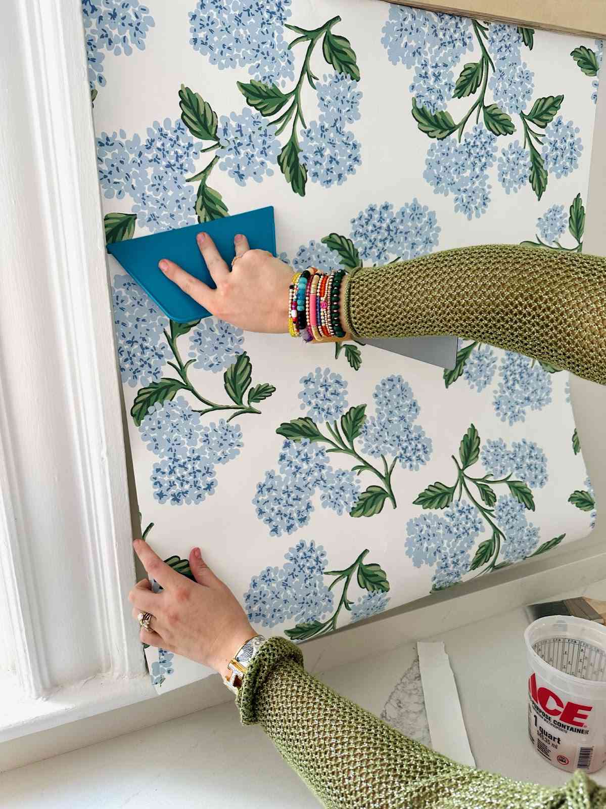 Clare lissant du papier peint sur un mur.