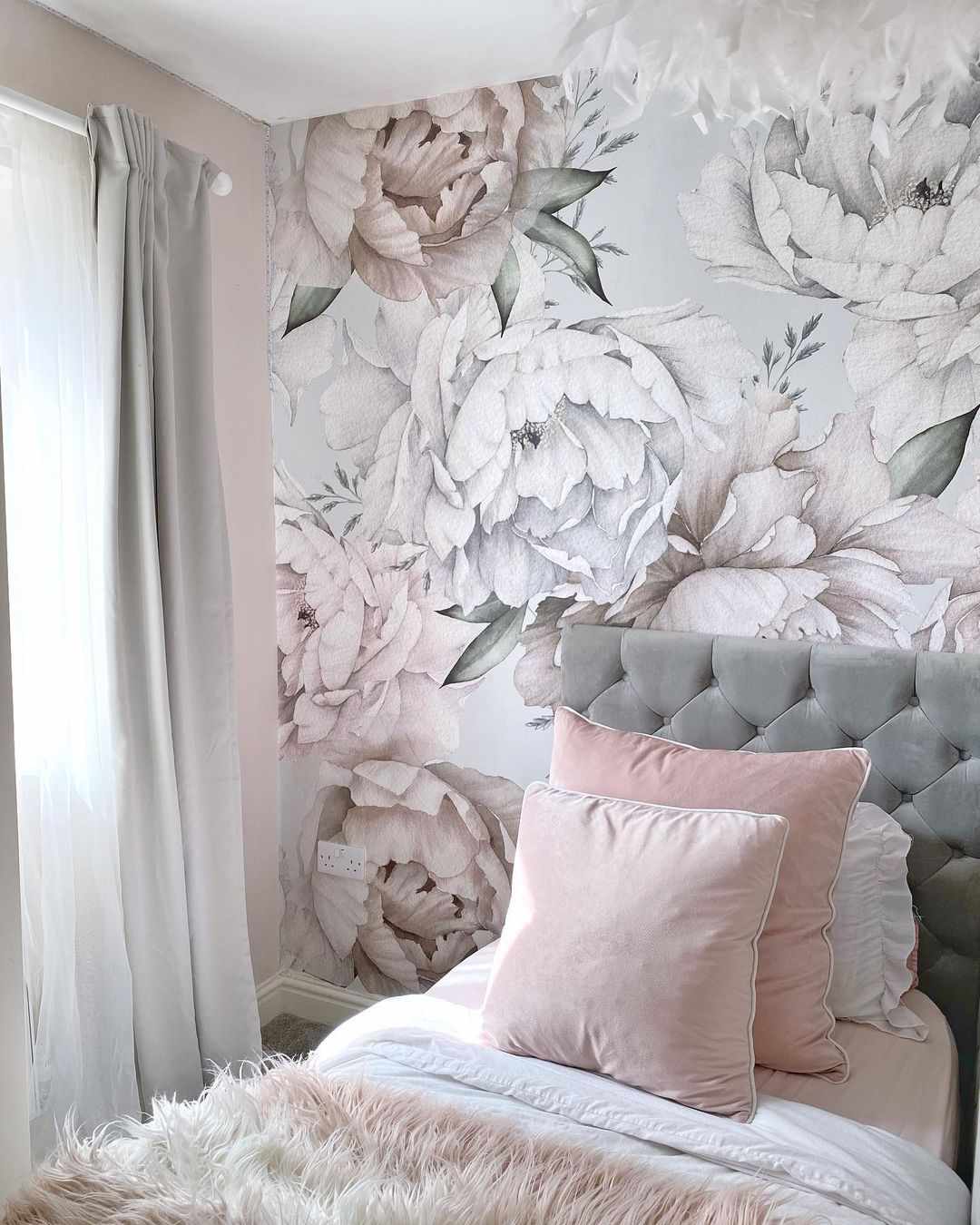 Papier peint à grands motifs floraux dans des tons sourds de gris et de rose dans la chambre d'une adolescente.