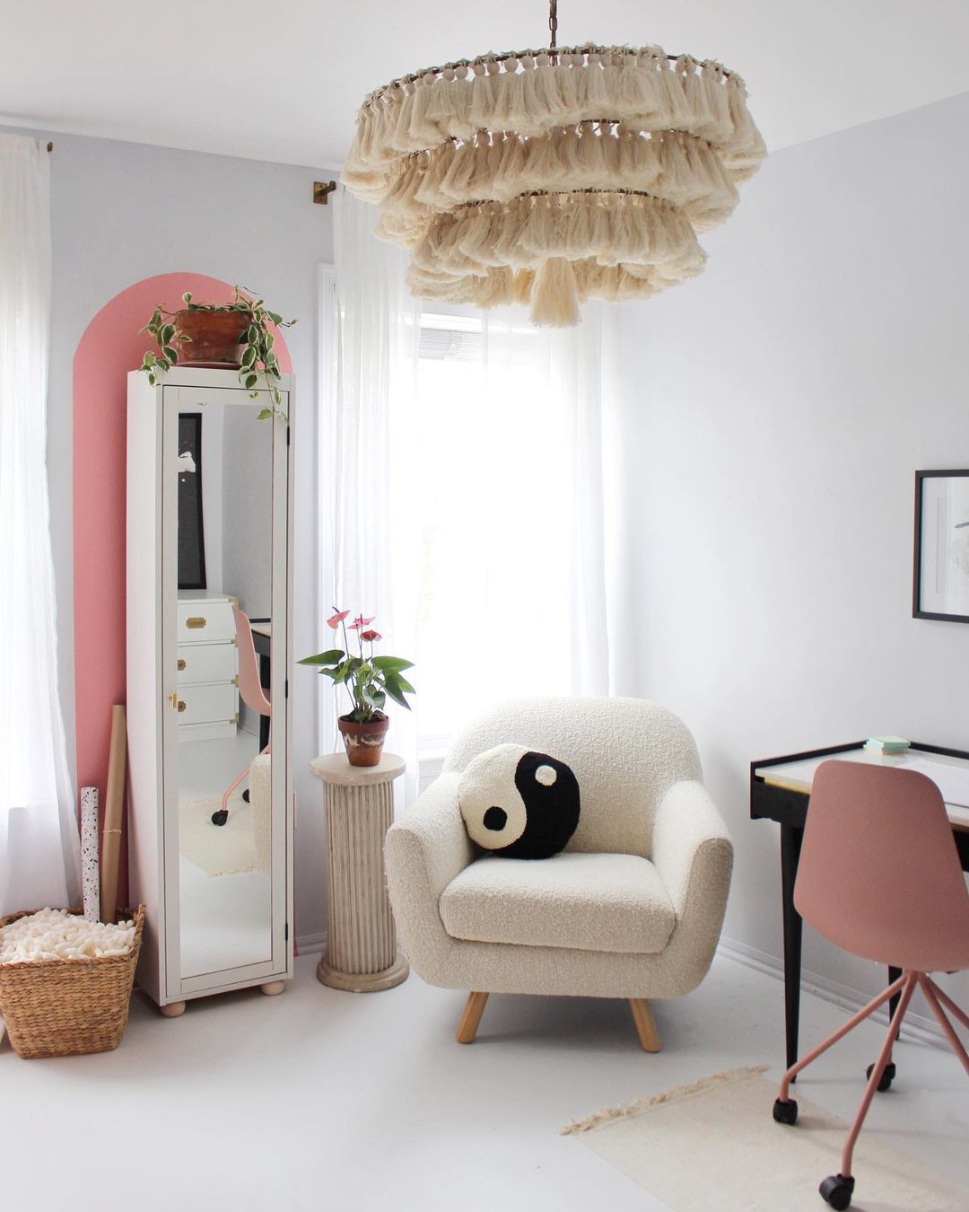 Une chambre d'adolescente avec un grand lustre à pampilles, un espace pour les devoirs et un fauteuil avec un coussin yin yang.
