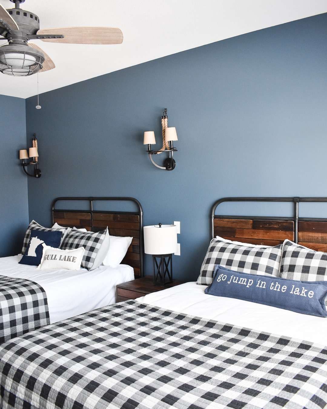 Cette chambre pour adolescents, inspirée par le lac, comprend deux lits avec une literie à carreaux noirs et blancs et des oreillers avec des mots sur le lac.