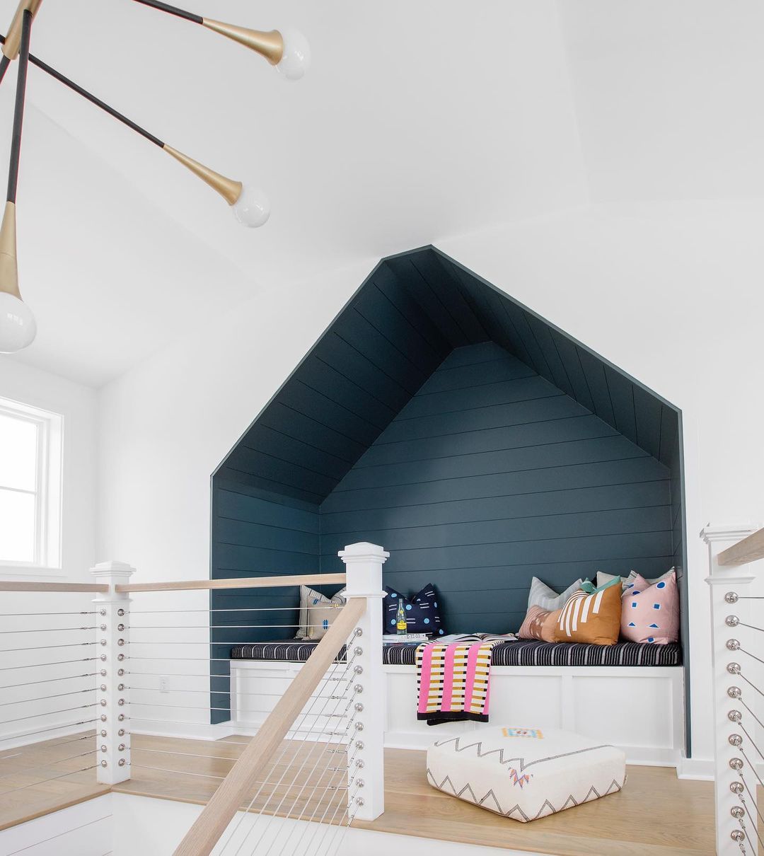 Un coin de détente pour les adolescents dans un loft peint en bleu et meublé d'un banc encastré et d'un assortiment de coussins de canapé.