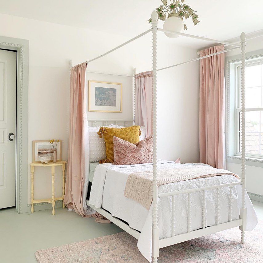 Une adorable chambre d'adolescente avec des rideaux roses suspendus à un lit à baldaquin.