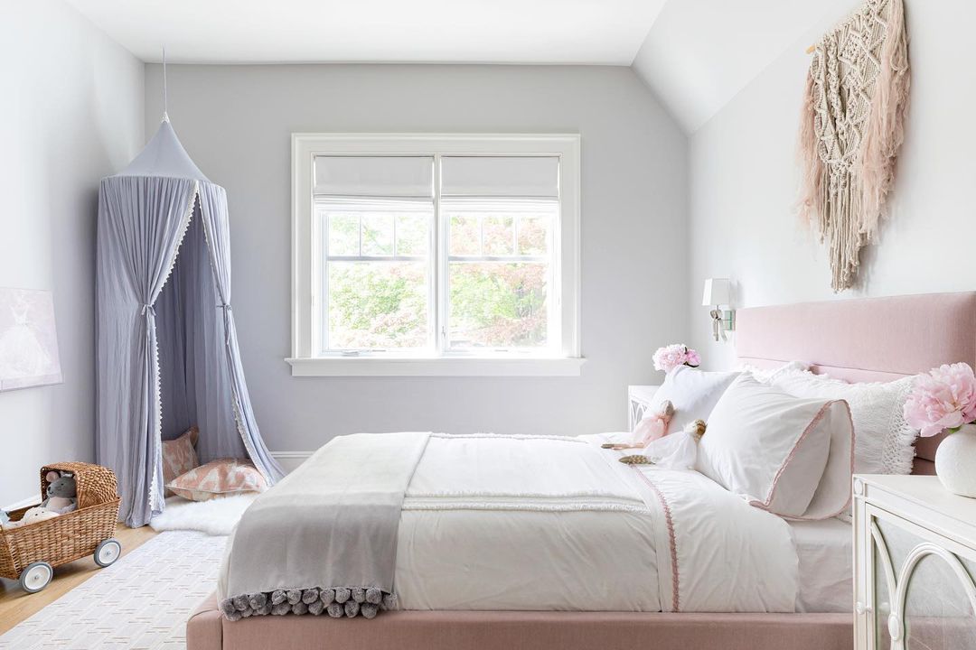 Une chambre de préadolescente avec une dizaine dans le coin, un lit capitonné rose et un grand macramé suspendu au-dessus du lit.