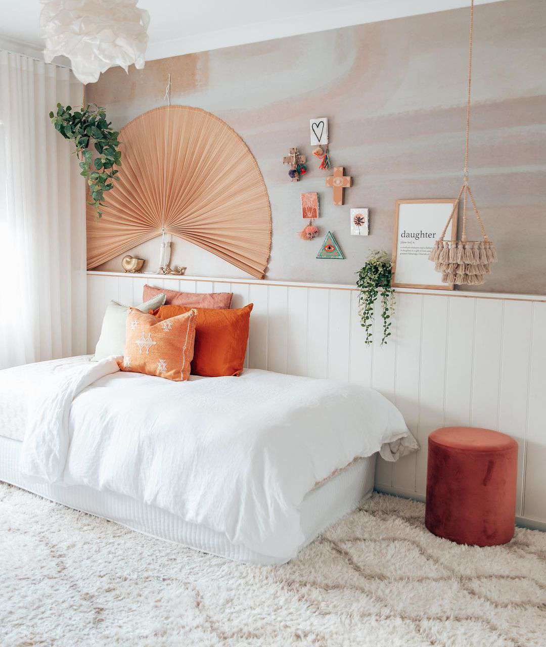 Une chambre d'ado d'inspiration bohème avec des murs en aquarelle, un grand ventilateur en papier, un lit de jour et une jardinière à pompons suspendue.