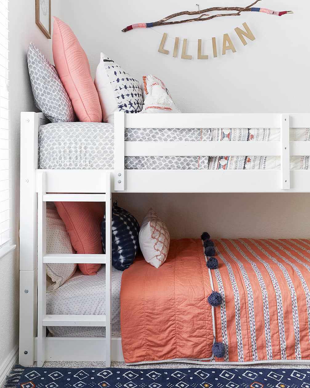 Une chambre d'adolescente partagée avec des lits superposés et une literie coordonnée en rose et bleu.