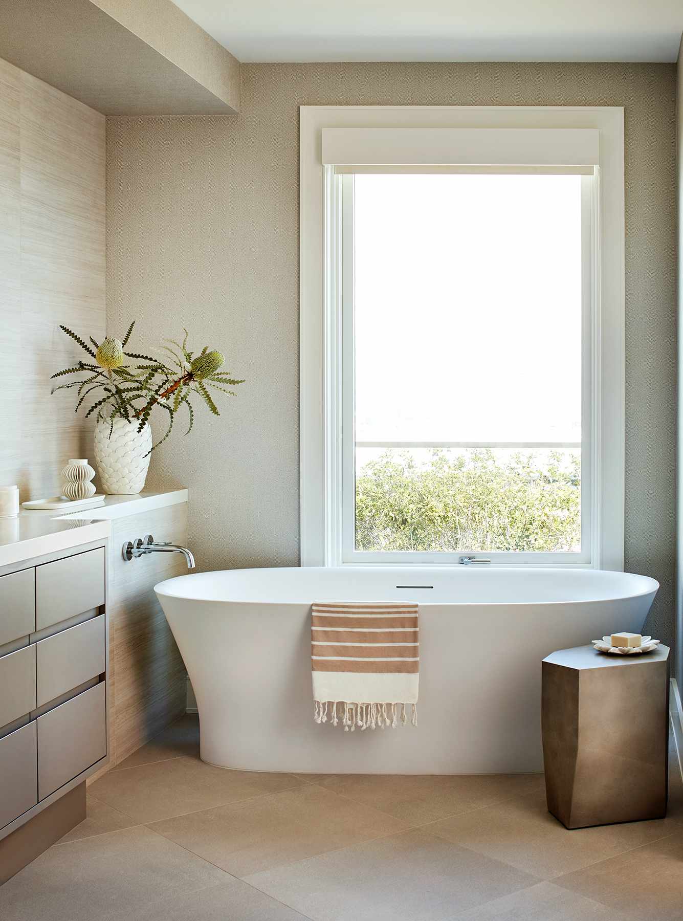 Une grande baignoire trône dans une salle de bains aux murs peints en beige.