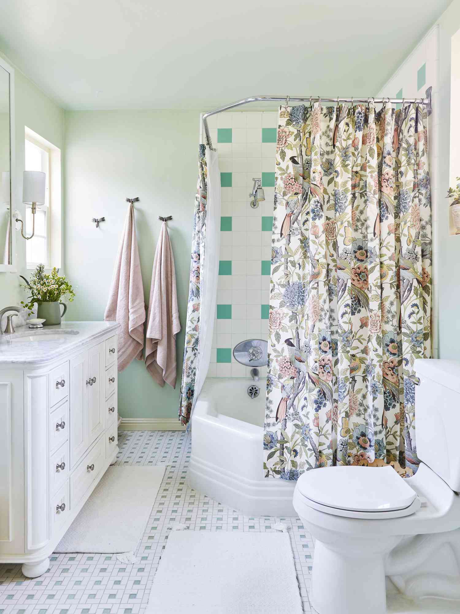 Un rideau floral lumineux avec des touches de beige pour fondre les fleurs et l'associer à la douche, au lavabo et aux toilettes blancs de la salle de bains.