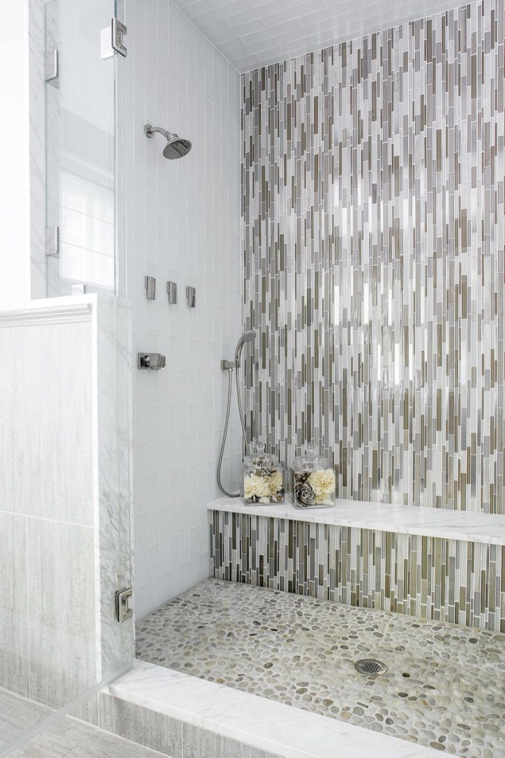 Une douche haute est carrelée avec des carreaux rectangulaires qui descendent le long du mur.