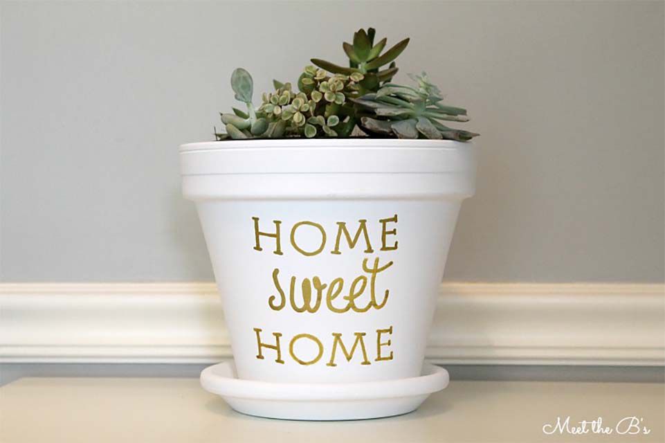 Un pot blanc sur lequel est écrit "Home Sweet Home" en lettres dorées.