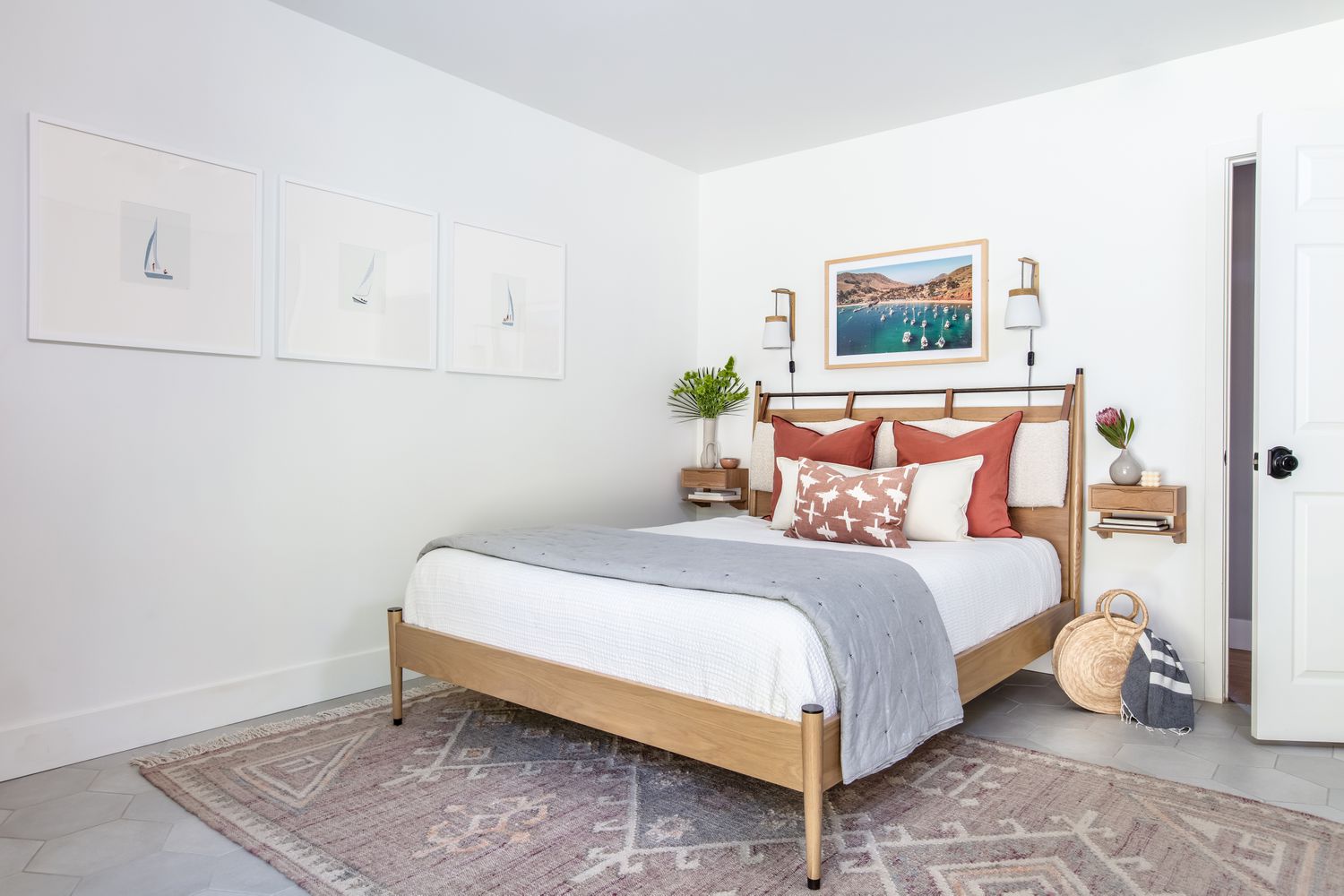 Une chambre à coucher a des murs blancs avec une nuance de gris froid qui s'accorde parfaitement avec l'image de voiliers au-dessus du lit.