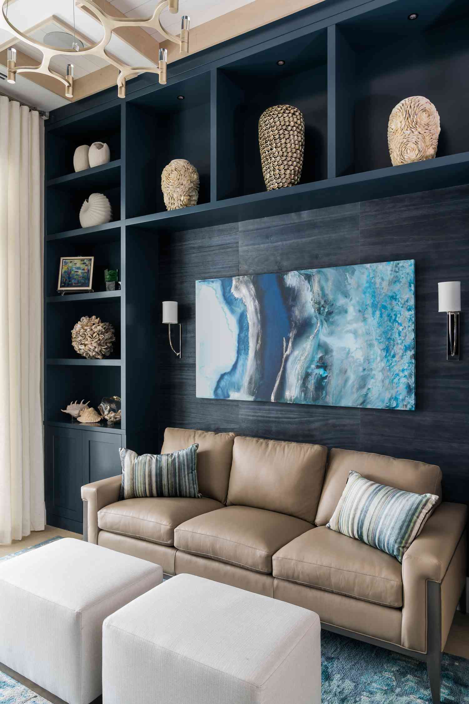 Des étagères encastrées en bois naturel ont été teintes en bleu marine. À l'intérieur des étagères se trouvent de nombreux vases et coquillages.