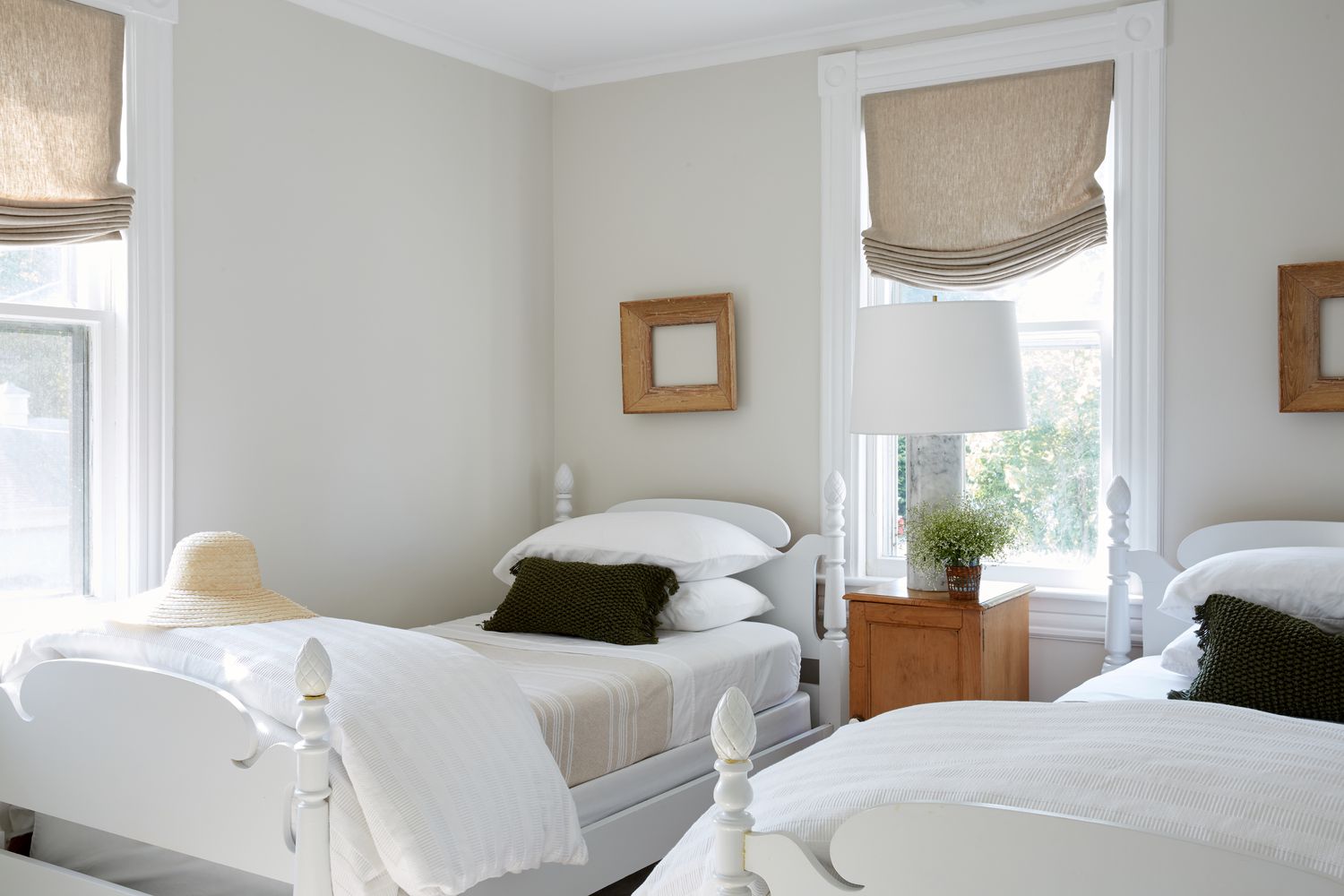 Une chambre avec des lits jumeaux présente des éléments en bois sur une base essentiellement blanche.