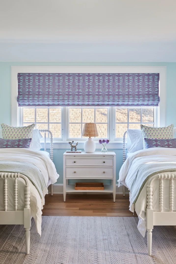 Abat-jour à motifs bleus et violets dans une chambre d'enfant à lits jumeaux.