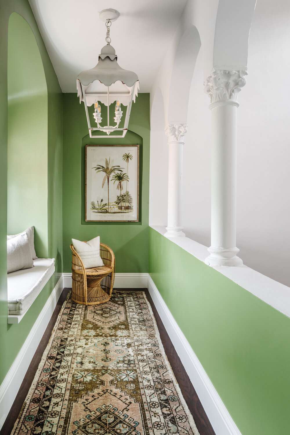 Couloir vert avec un siège de fenêtre et une lampe suspendue blanche ornée.