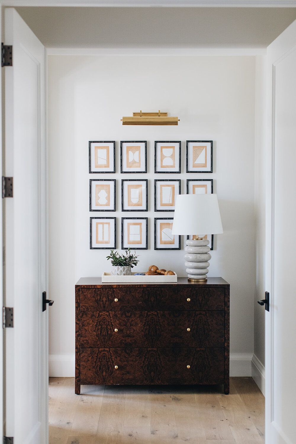 Couloir étroit avec une armoire et un mur d'art au-dessus.