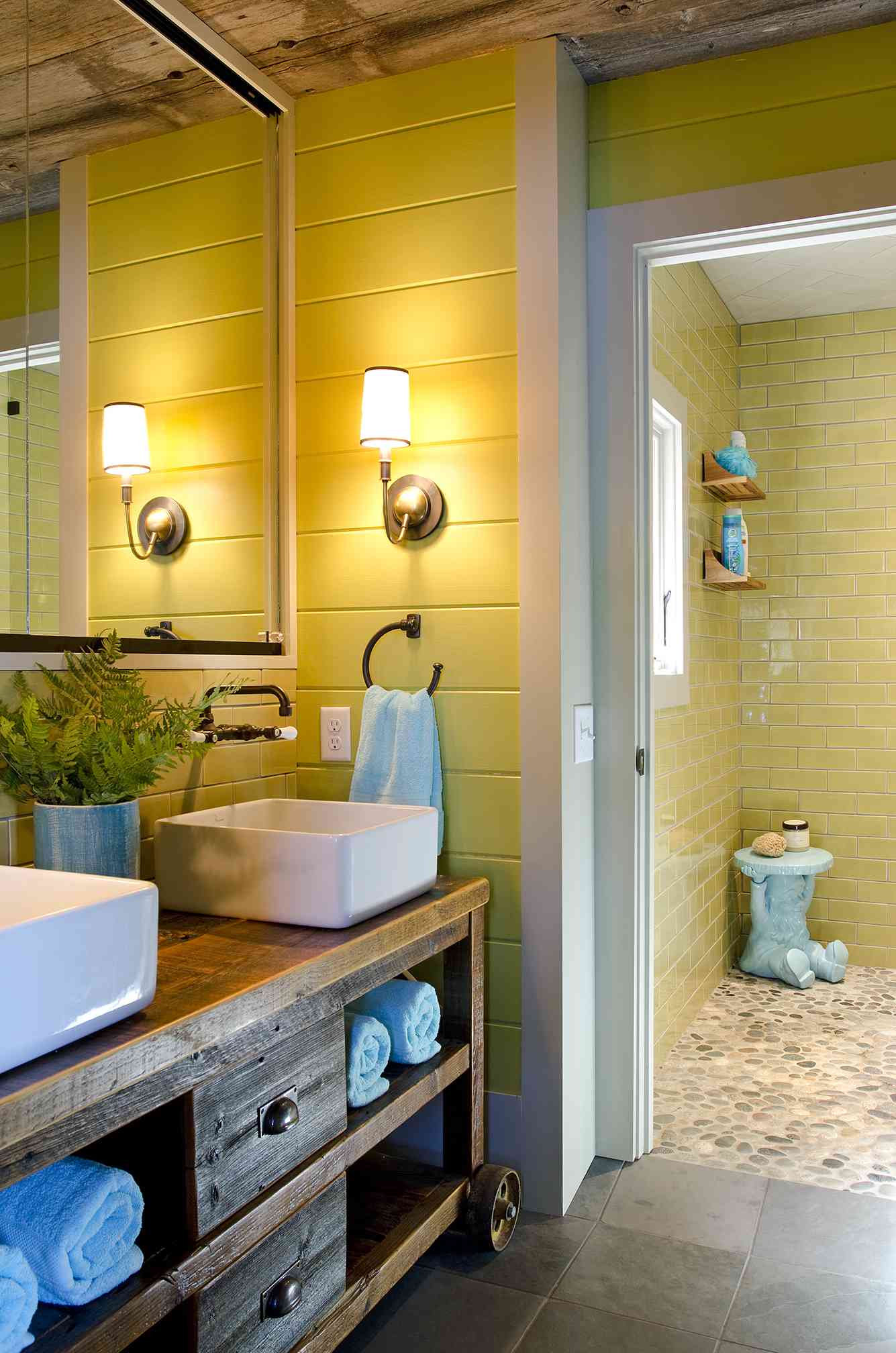 Salle de bain jaune rustique avec shiplap, meuble-lavabo en bois vieilli et douche en carreaux de métro jaunes.