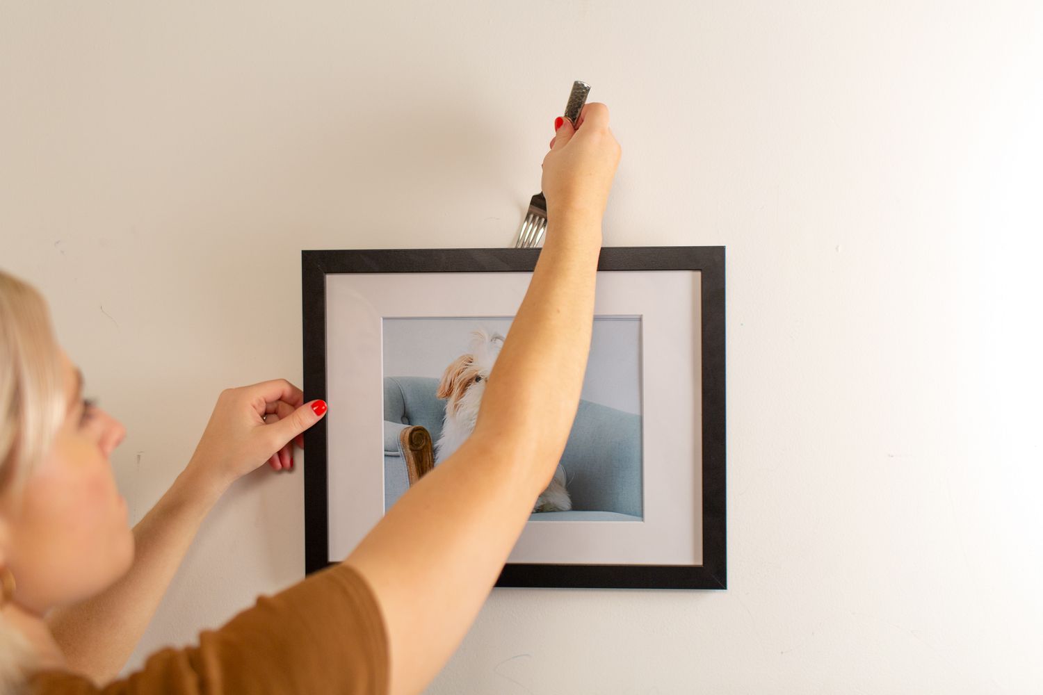 Femme accrochant un cadre photo avec une fourchette