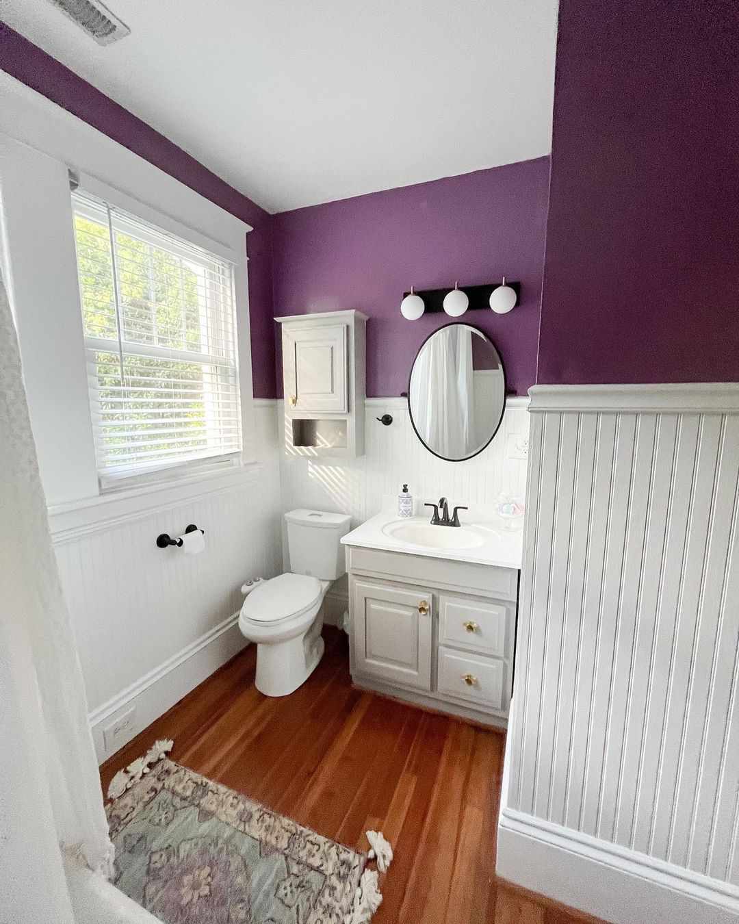 Salle de bains avec des panneaux muraux blancs et de la peinture violette.