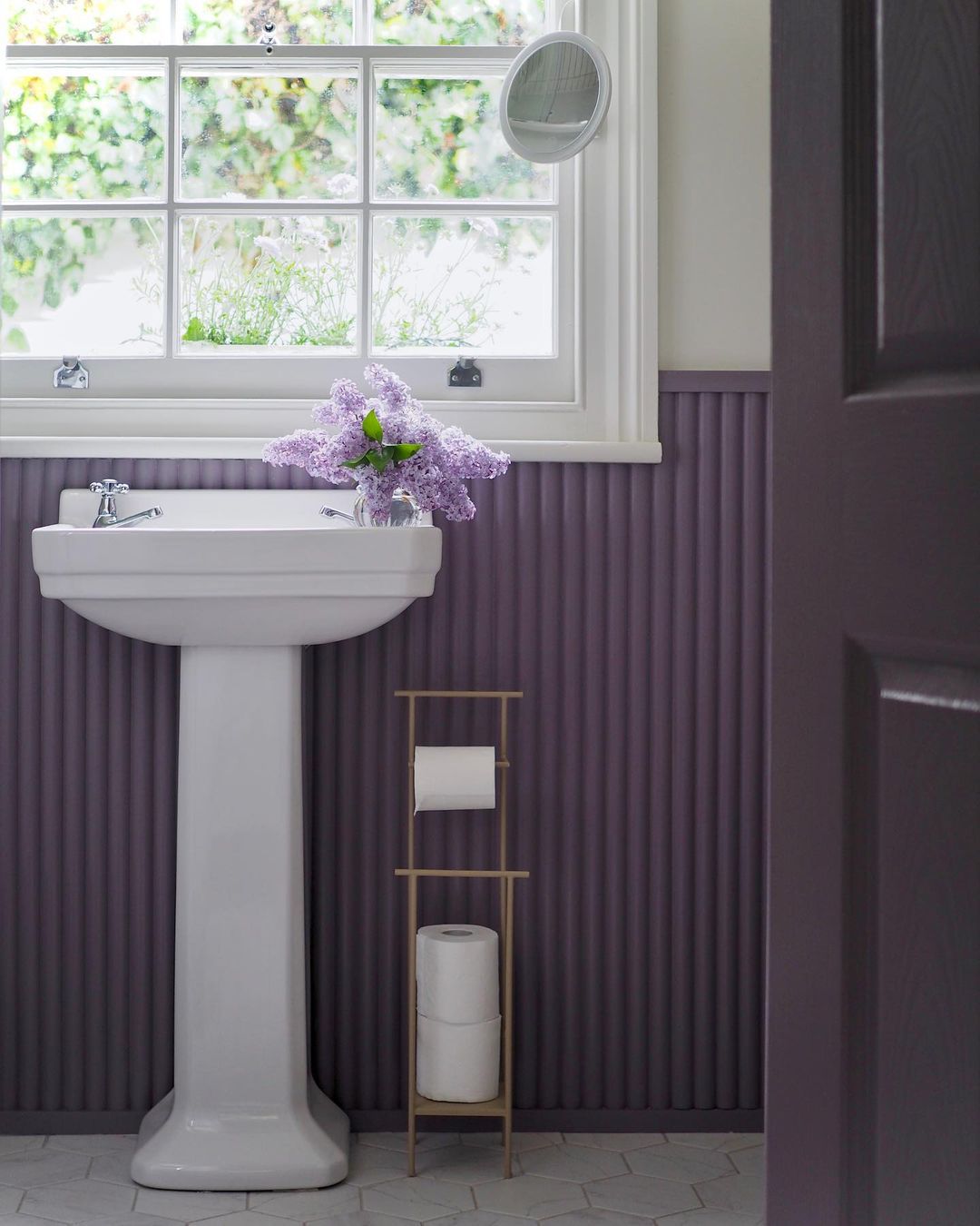 Salle de bains avec panneaux muraux violets et porte assortie.