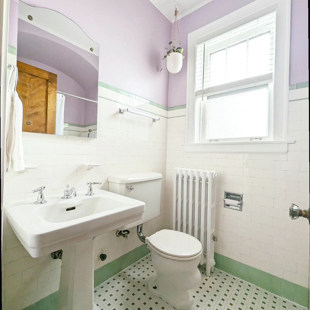 Salle de bain de style vintage avec des murs violets et du carrelage vert menthe.