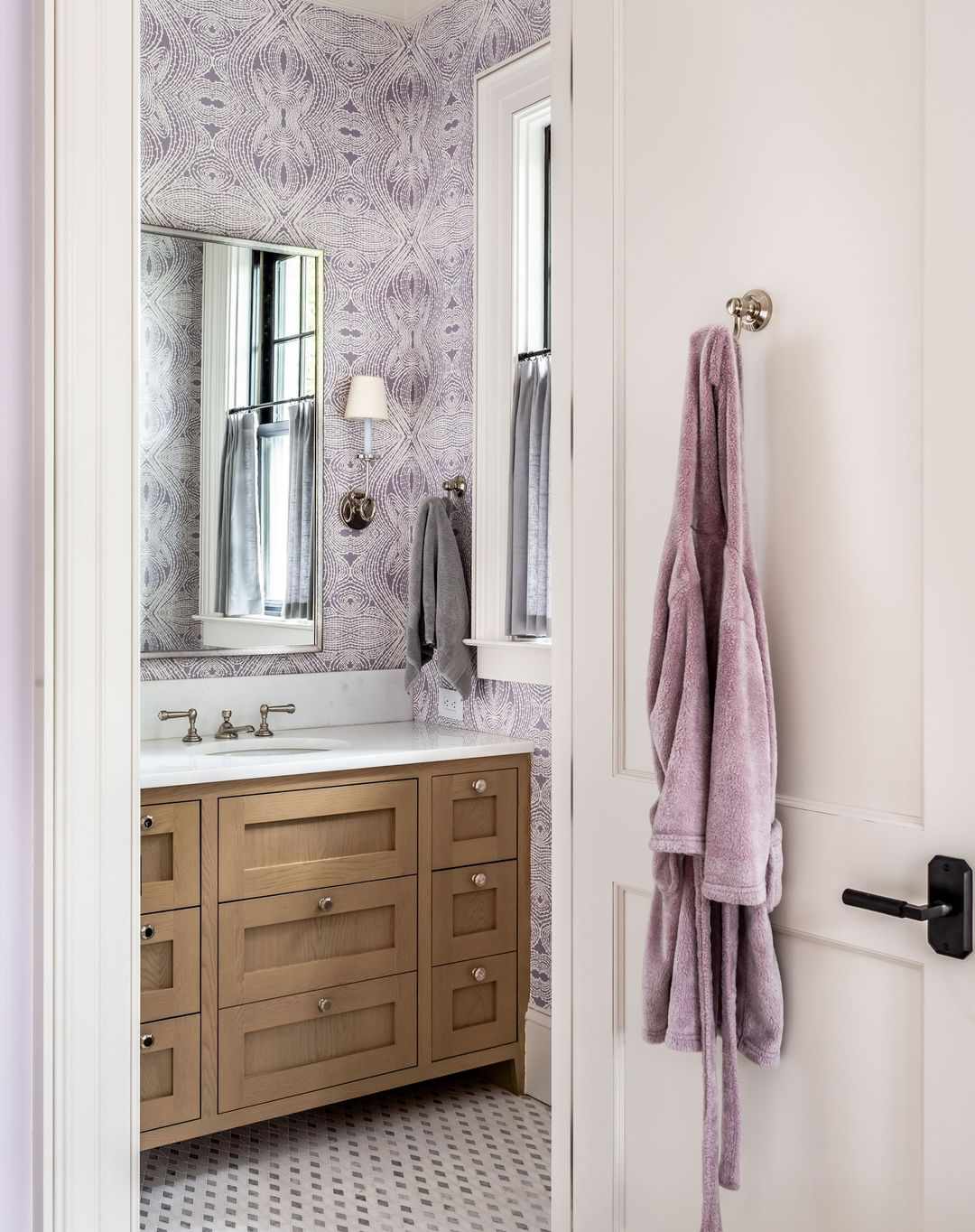 Salle de bains sereine et apaisante avec un papier peint orné violet et blanc.