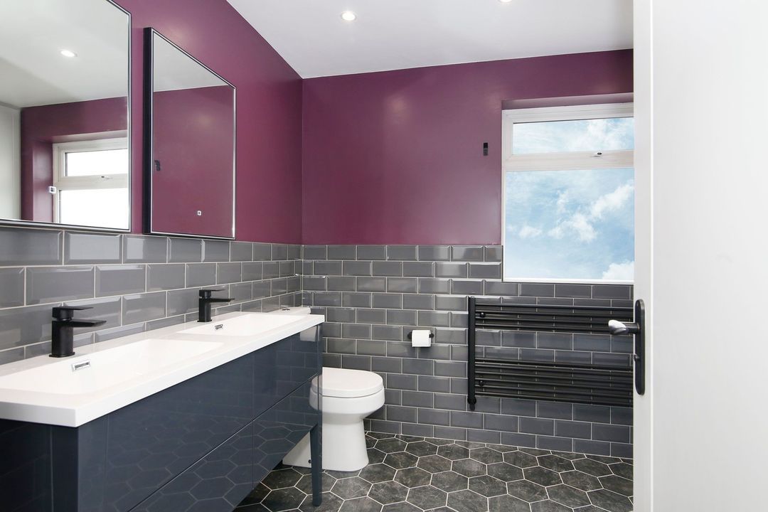 Grande salle de bains avec carrelage gris et peinture murale violette.